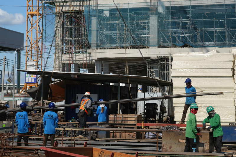 A group of workers in blue and green uniforms work on a construction site