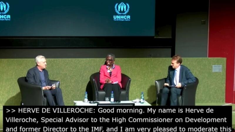 Three UNHCR members talking on stage 