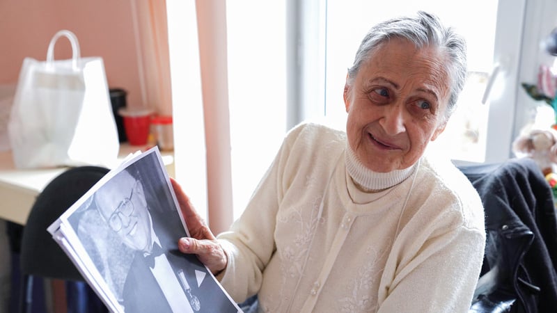 Victoria Logvinova, a former conductor from Ukraine, holds a black-and-white photograph of Viacheslav Serhiiovych Palkin (1935–2008), a renowned Ukrainian conductor and composer who played a significant role in shaping her musical career.