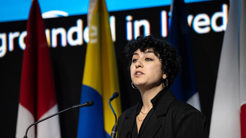 A woman speaks into a microphone on stage.