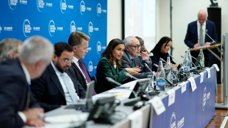Several speakers sit behind a long panel table with GRF branding. 