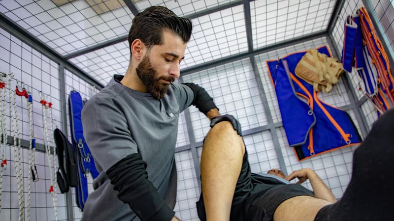 Fawaz holds the knee and ankle of a patient during a physiotherapy session