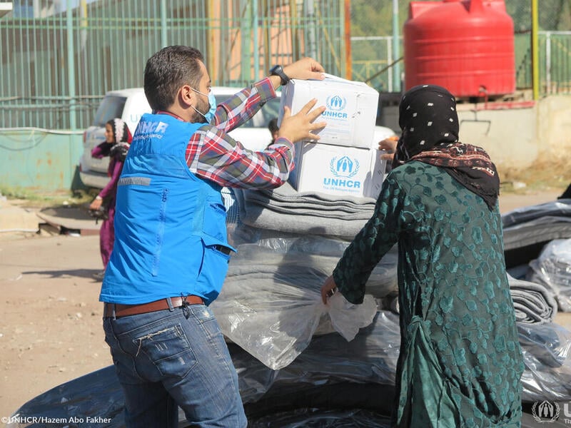 Two people unpack UNHCR boxes and blankets in Syria 