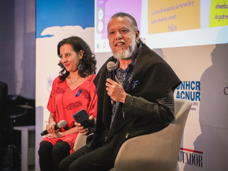 Alberto Dinero on stage talking into a microphone.