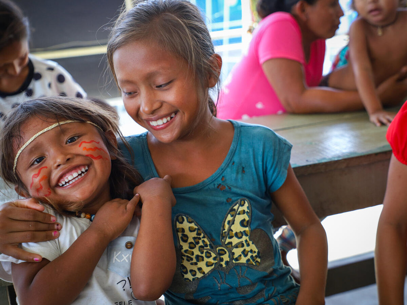 Two young girls play together and smile at the camera.
