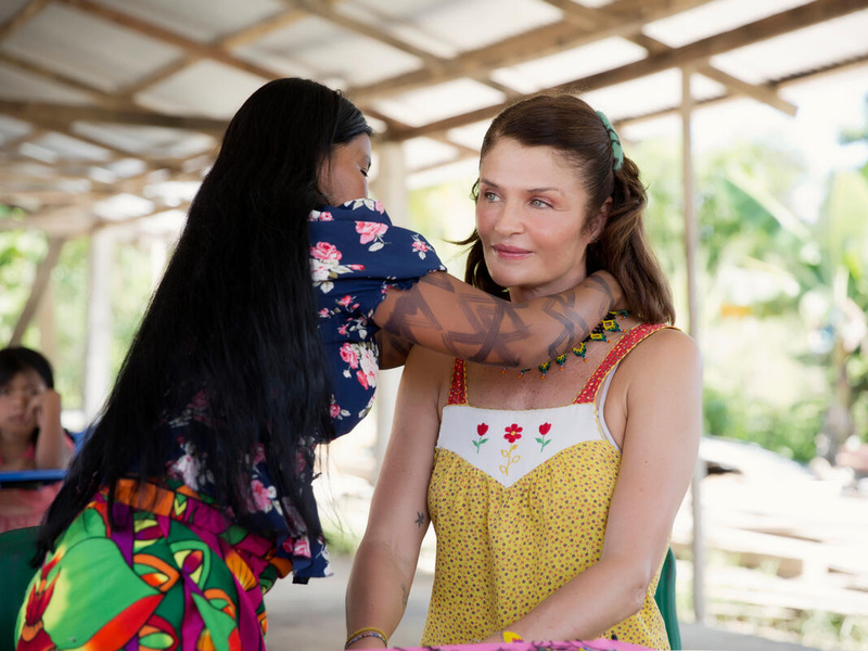 Floriselda Chamapuro putting jewely around Helena Christensen's neck