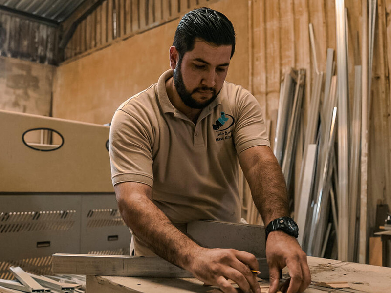 A carpenter measures wood in a workshop.