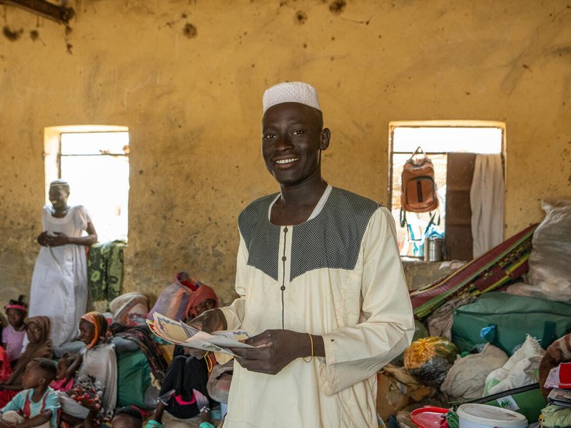 شاب يحمل بعض الوثائق في غرفة مزدحمة.