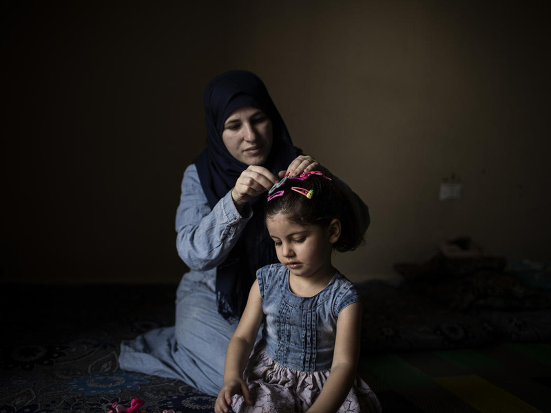 A Syrian woman does her daughter's hair.