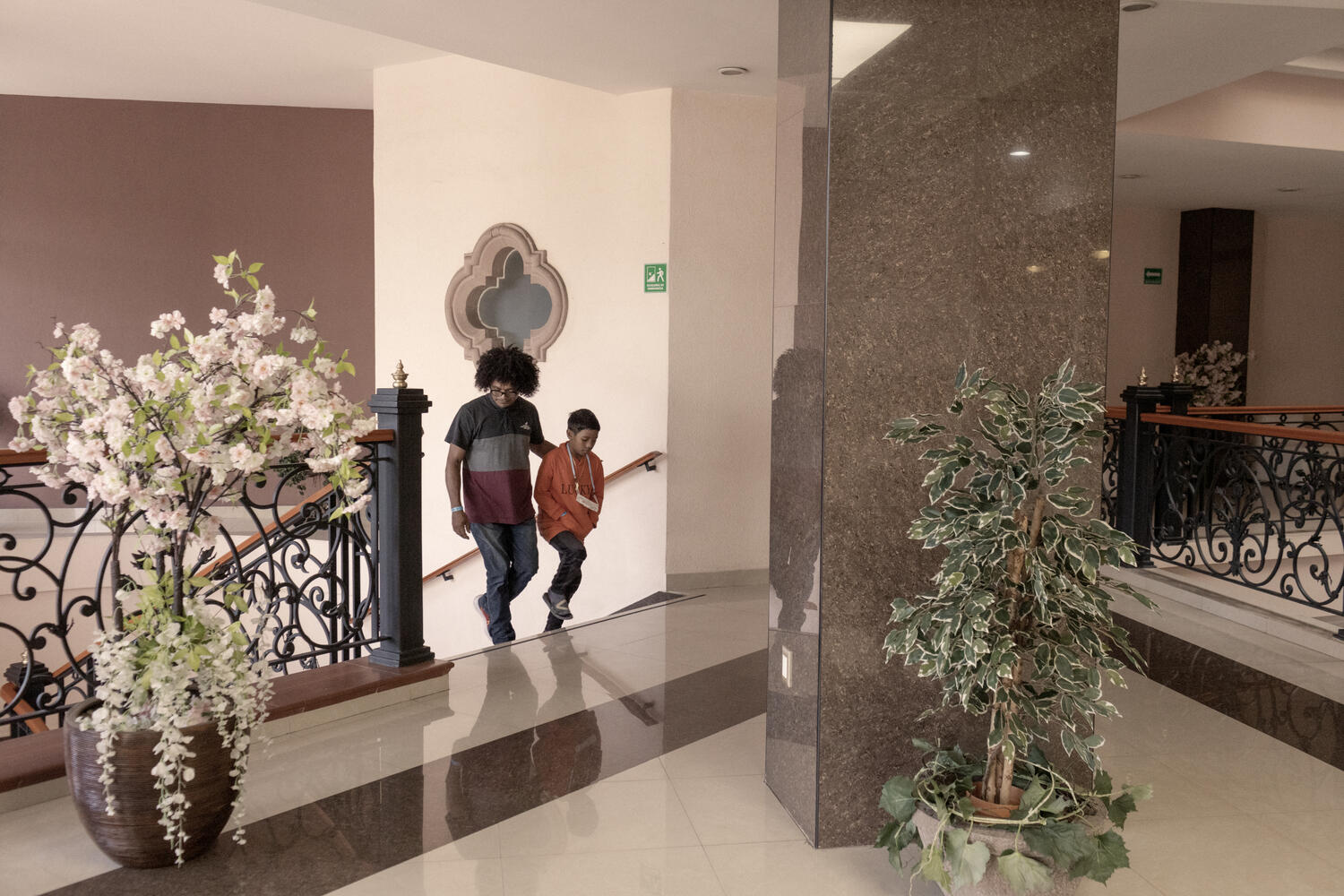 A man and a boy walk up some stairs in a hotel.
