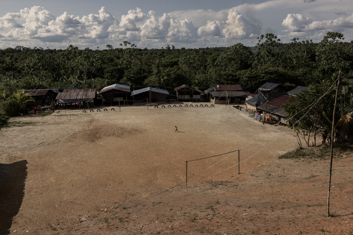 A dirt square and a few houses make up a village on the edge of the jungle.