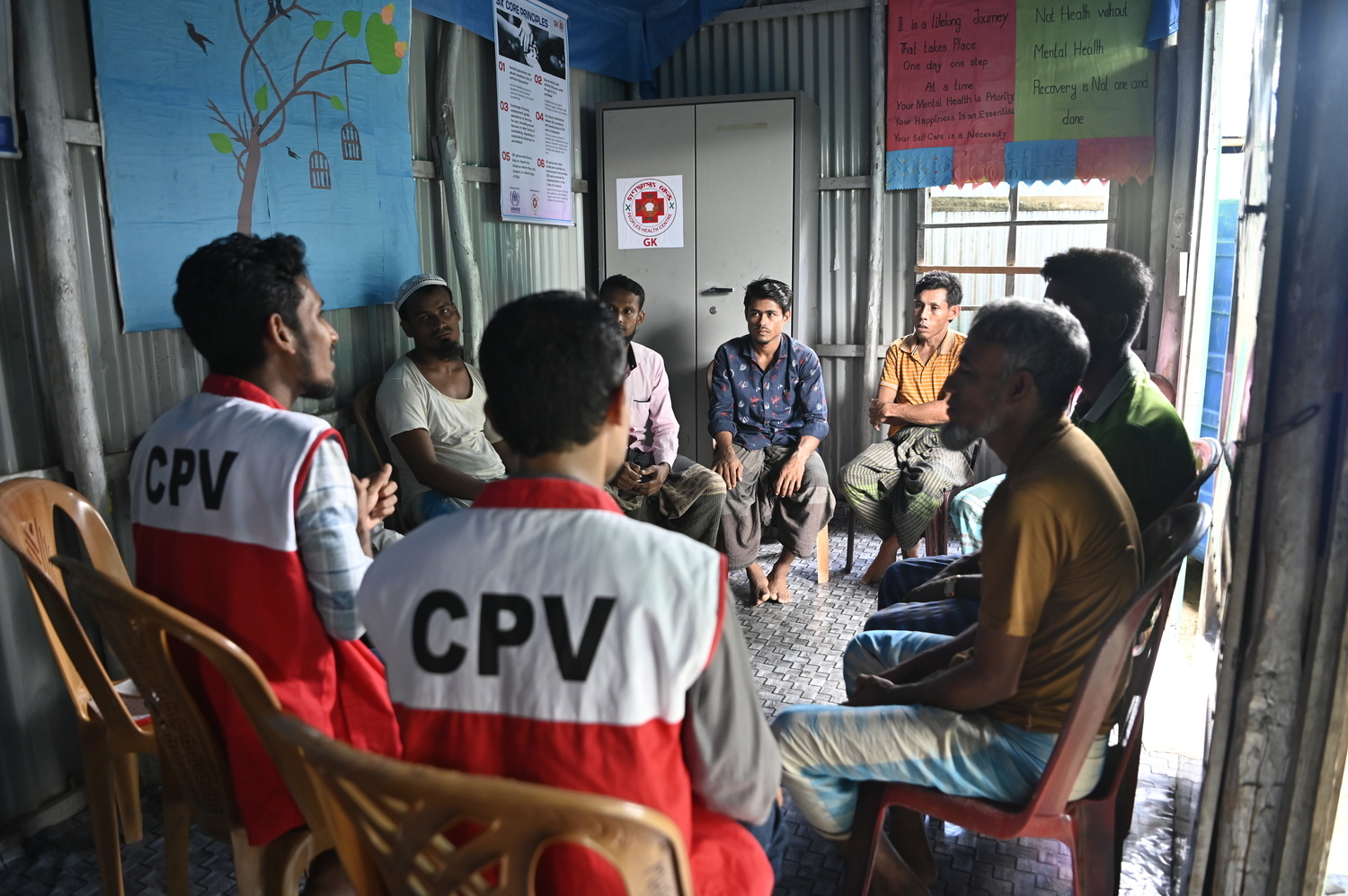 Volunteers conduct a group support session on positive parenting for Rohingya refugee men.