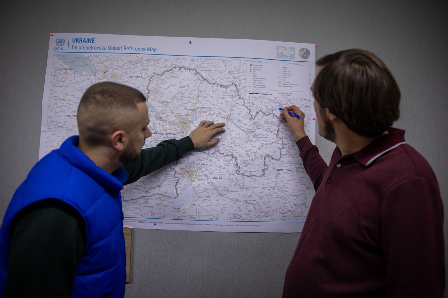 Two men consult a wall map of Dnipropetrovsk Oblast in eastern Ukraine