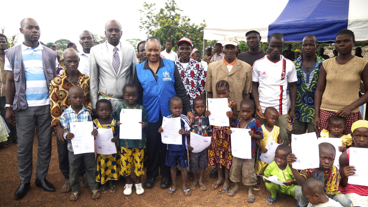 Barbara Hendricks stands with children holding their birth certificates.
