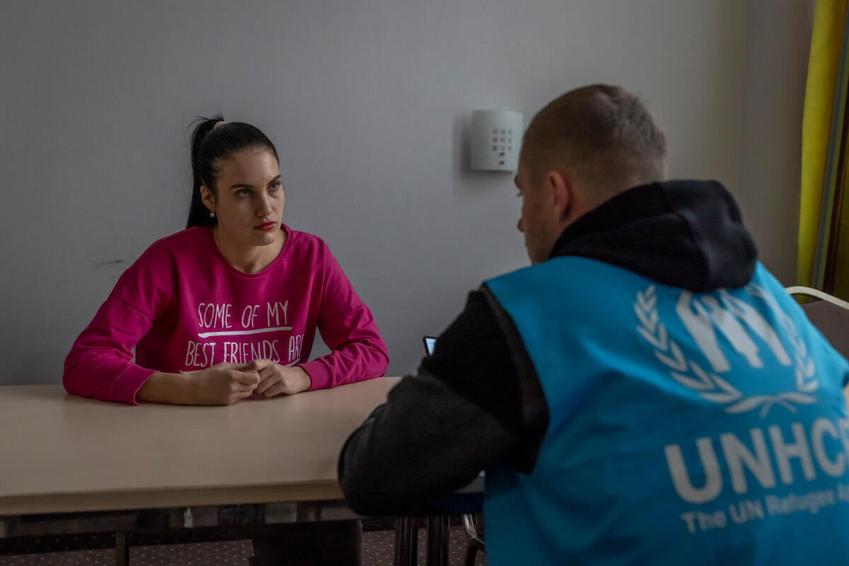 UNHCR worker Dmytro sits across a table from a refugee from Ukraine.
