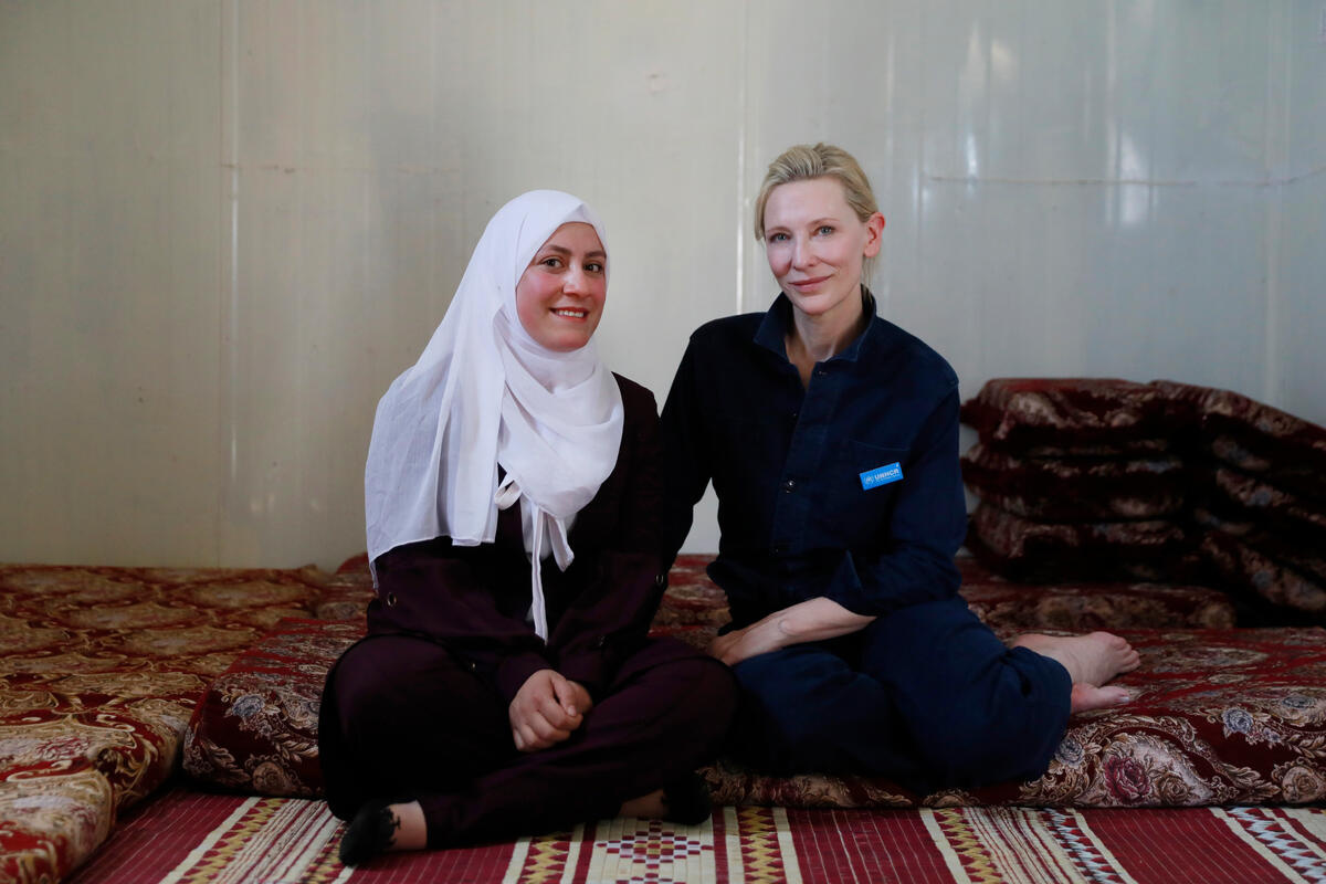 Cate and Alaa sitting on the floor, smiling at the camera
