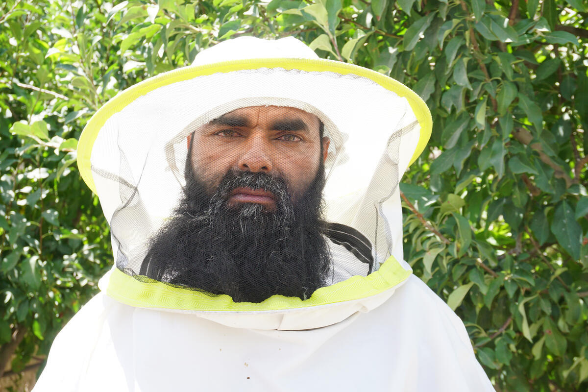 A man with beard wearing a white bee-keeping suit