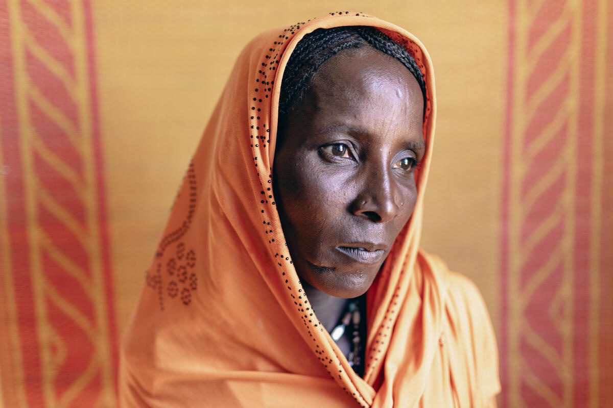 A portrait of a woman wearing an orange headscarf. 