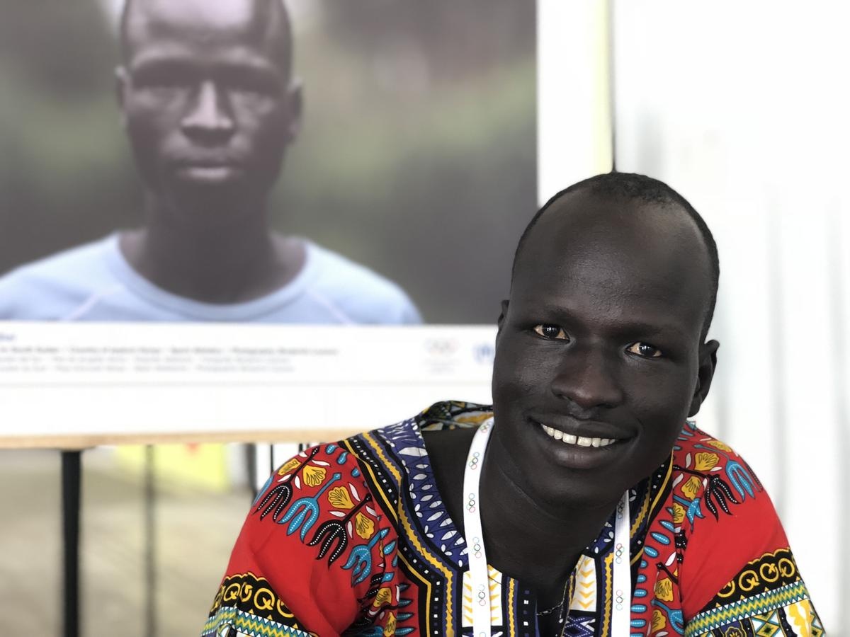 Pur Yiech Biel poses next to a photo of himself taken during the Rio 2016 Olympic Games.