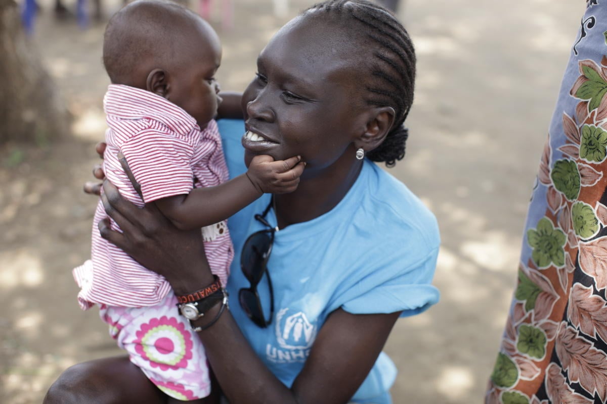 Alek Wek holds a baby in her arms.