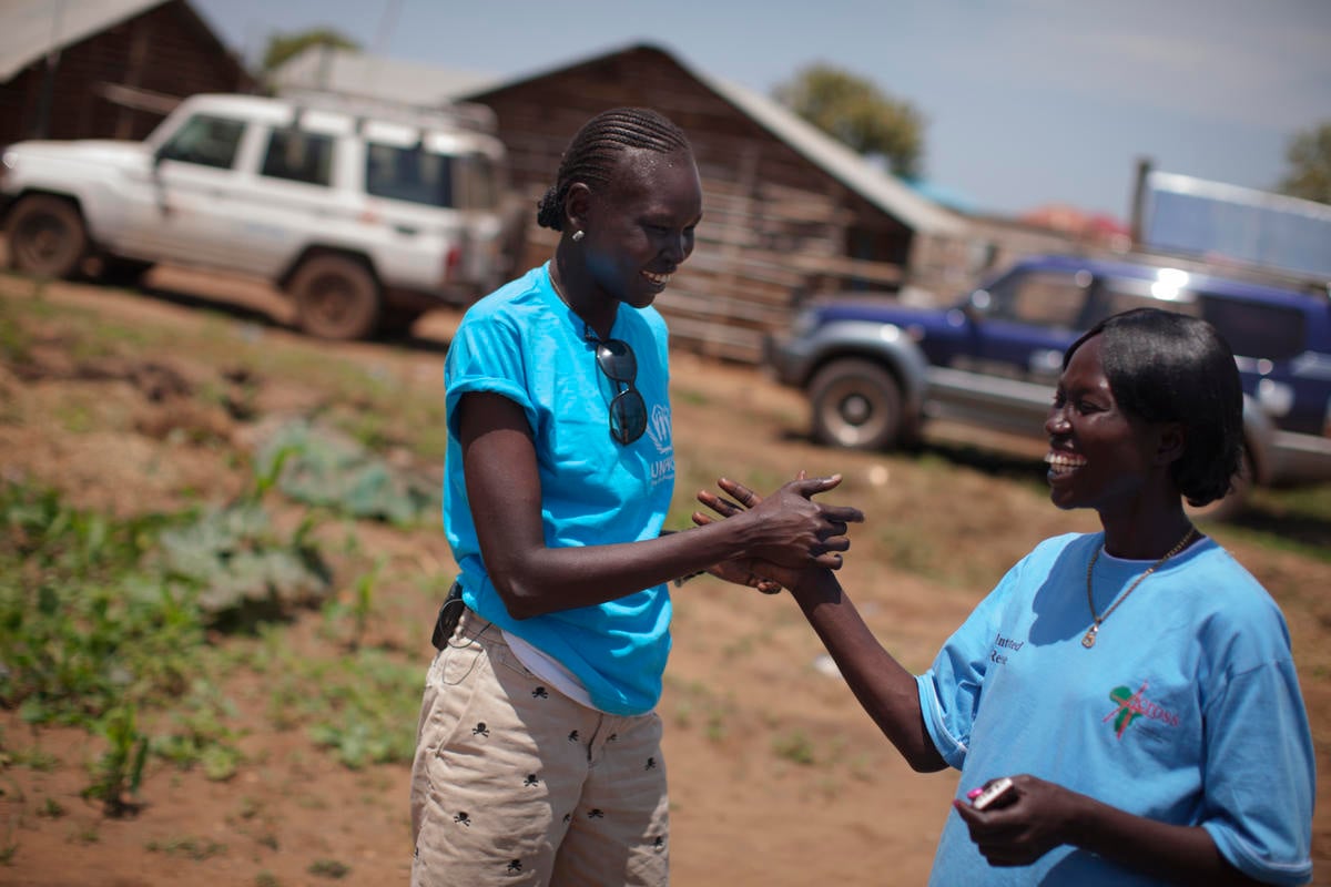 Alek Wek shakes hands with another woman.