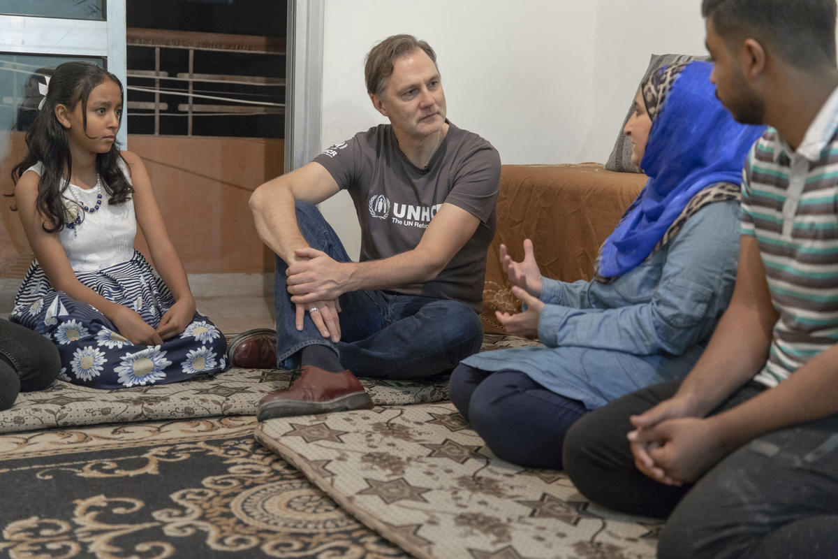 David Morrissey sits on the ground inside a house with a family of Syrian refugees.
