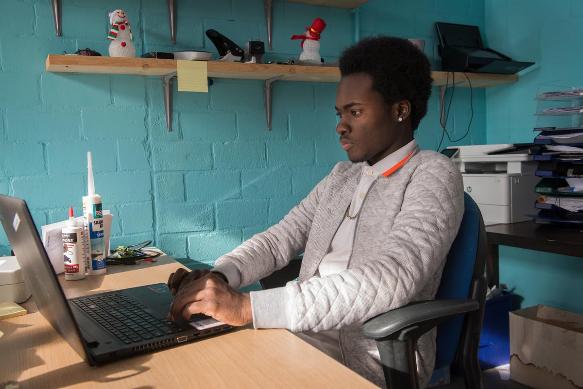 A man sits at his desk working at a laptop