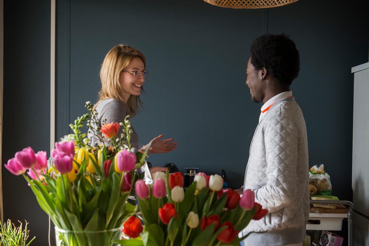 Two friends smiling behind vases of tulips