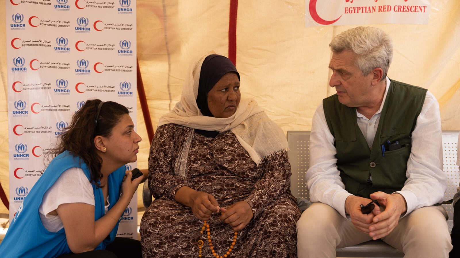 Filippo Grandi s'entretient par l'intermédiaire d'un interprète à une réfugiée soudanaise à l'intérieur d'une tente dans le sud de l'Égypte.
