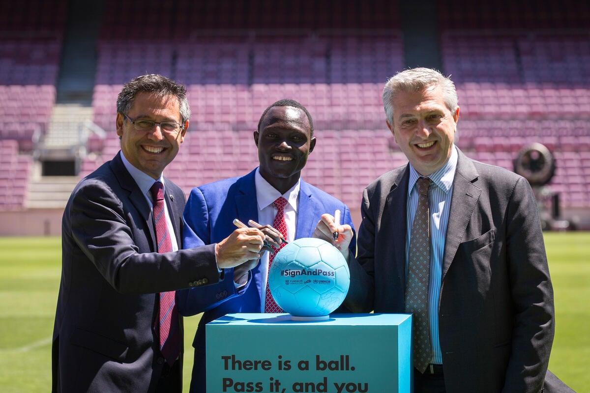 Spain. Josep Maria Bartomeu, Paulo Lokoro and Filippo Grandi sign off the ball of the #SignAndPass campaign in the Camp Nou footbal field.