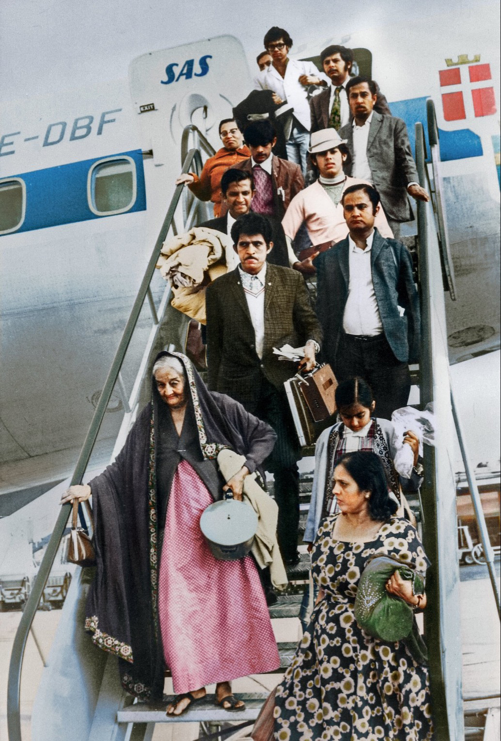 A group of people descending the stairs from an SAS plane