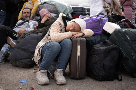 Zahraa, 12, sleeps on a suitcase on the roadside. 