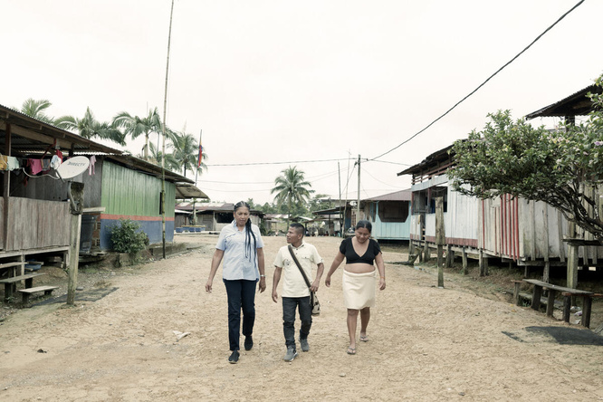 Three people walk together through a small village