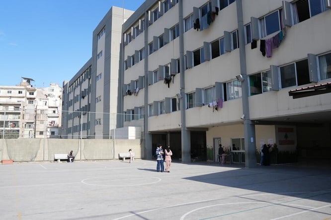 A view of a playground and school building with laundry hanging on lines out of the windows