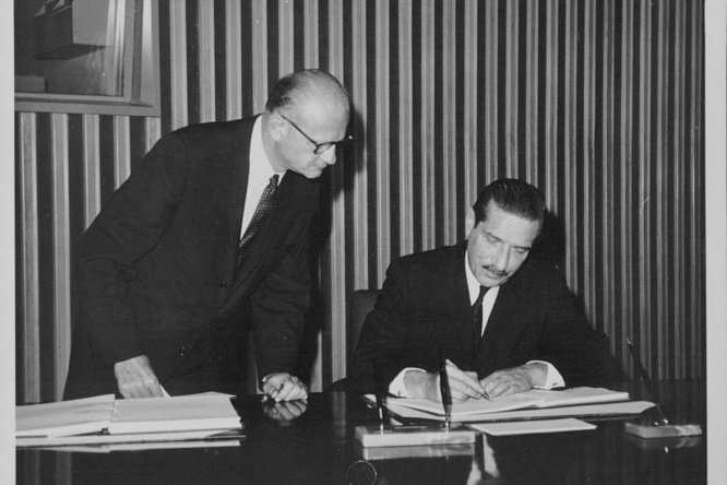 Black and white photograph of a man signing the final act of the Convention on the Reduction of Statelessness.