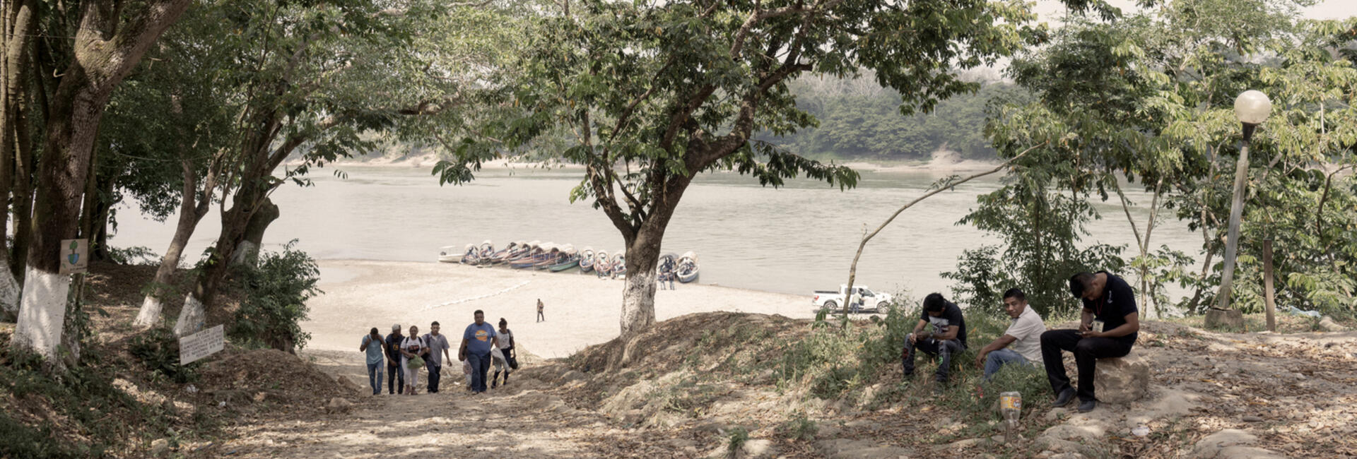 A group of people walk away from a river bank.