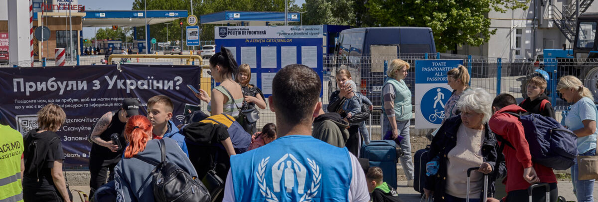 A UNHCR staff member provides assistance to a large group of Ukrainian refugees, who gather with their belongings in Moldova after crossing the border.
