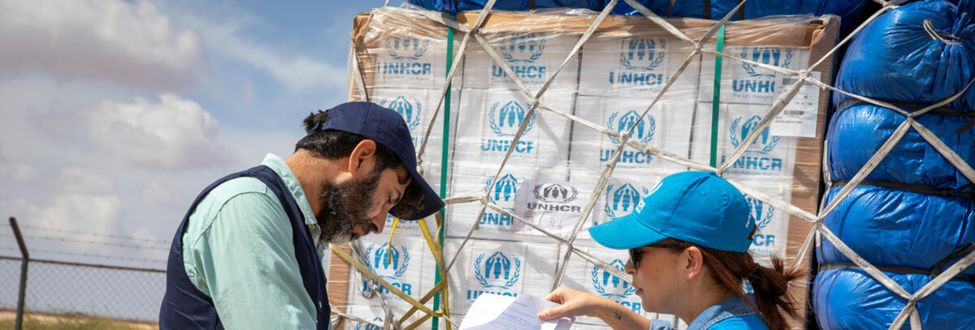 Two UNHCR staff members check a shipment of emergency supplies against a list
