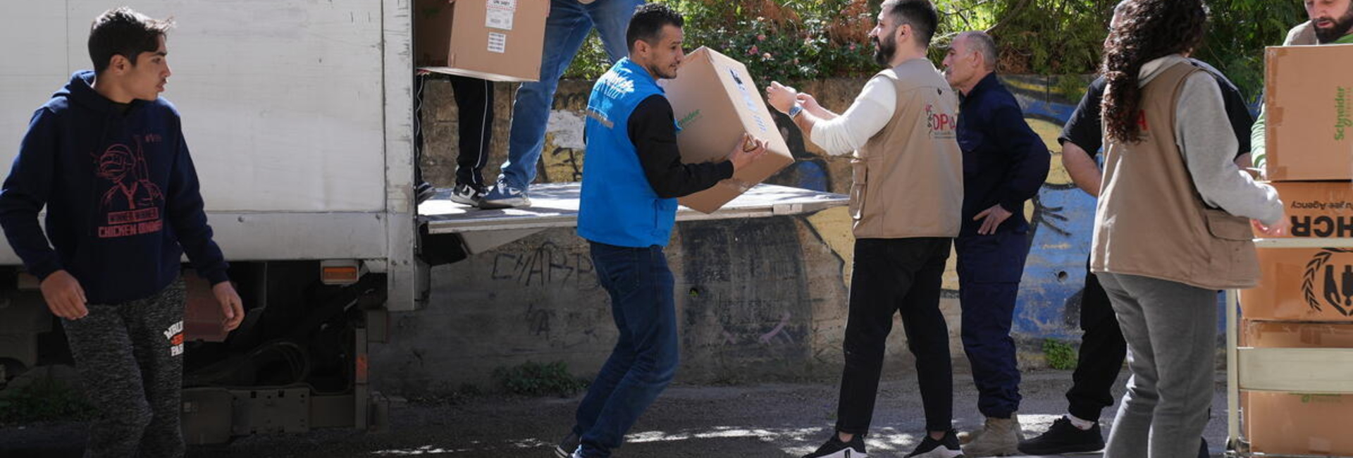 A group of people move boxes from the back of a truck
