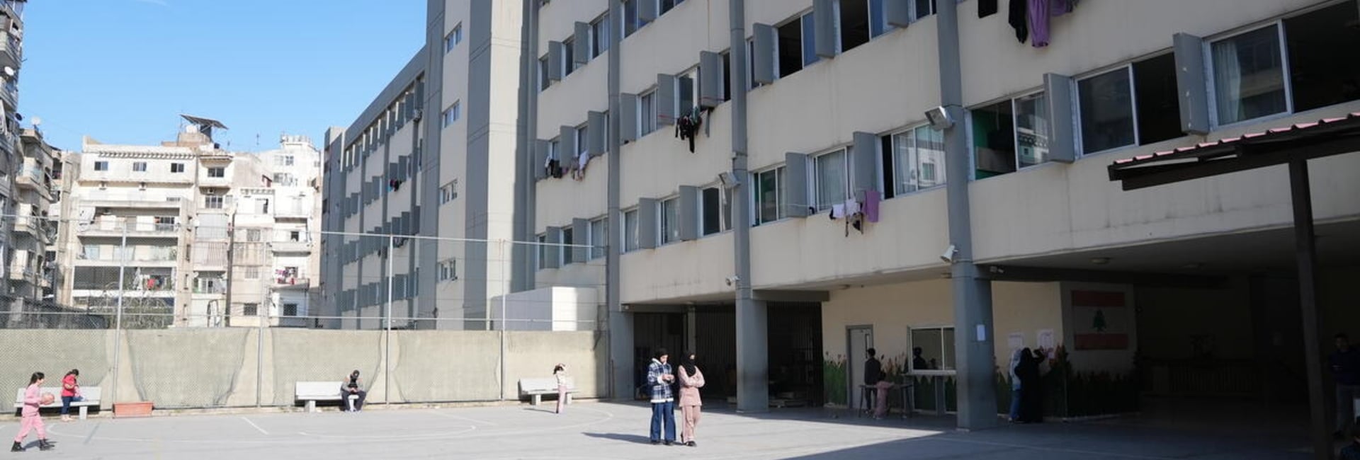 A view of a playground and school building with laundry hanging on lines out of the windows
