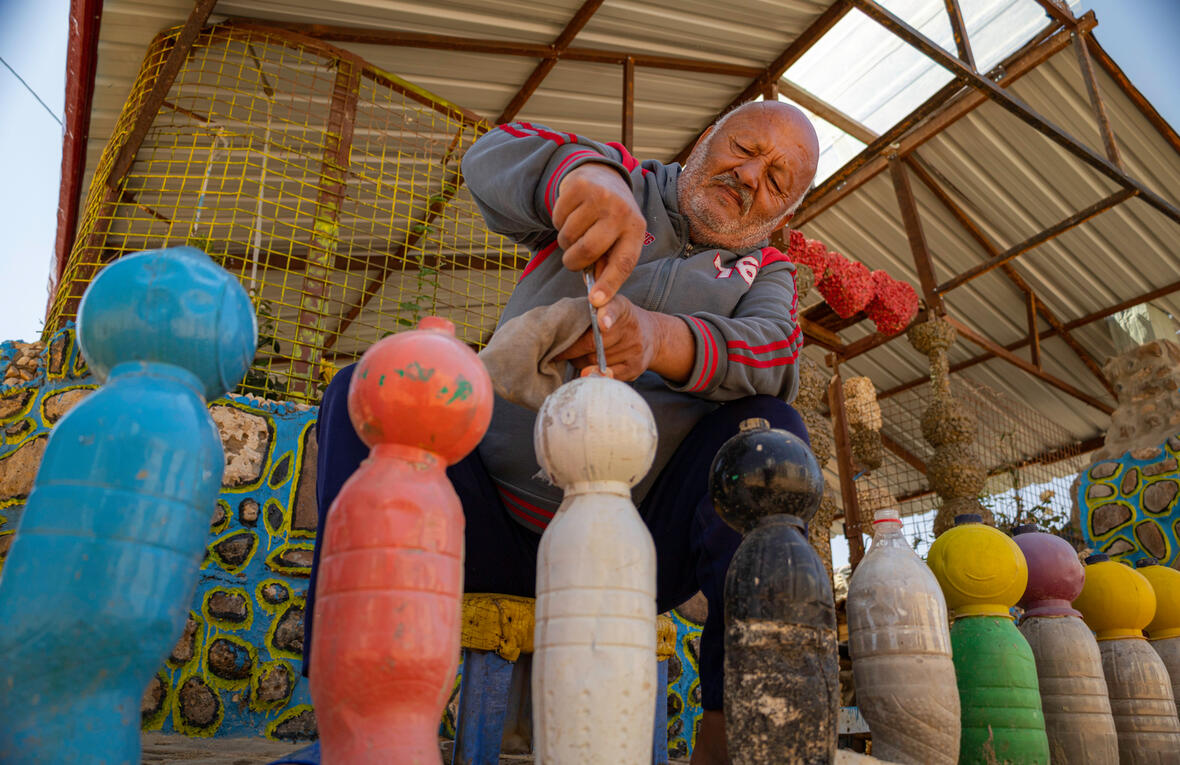 A man creates bollards from painted plastic bottles.