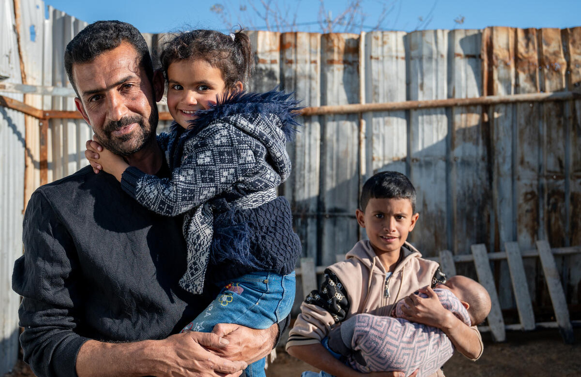 A father holds his daughter while his eldest son holds a baby