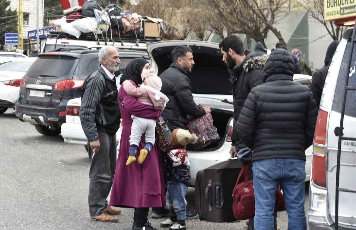 People gather at the back of a parked car at the Masnaa border point in Lebanon, waiting to cross into Syria