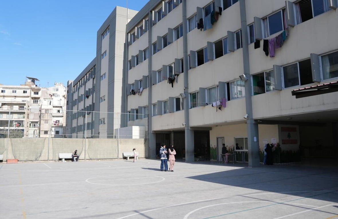A view of a playground and school building with laundry hanging on lines out of the windows