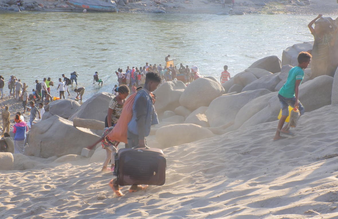 Ethiopian refugees flee across a river with their belongings.