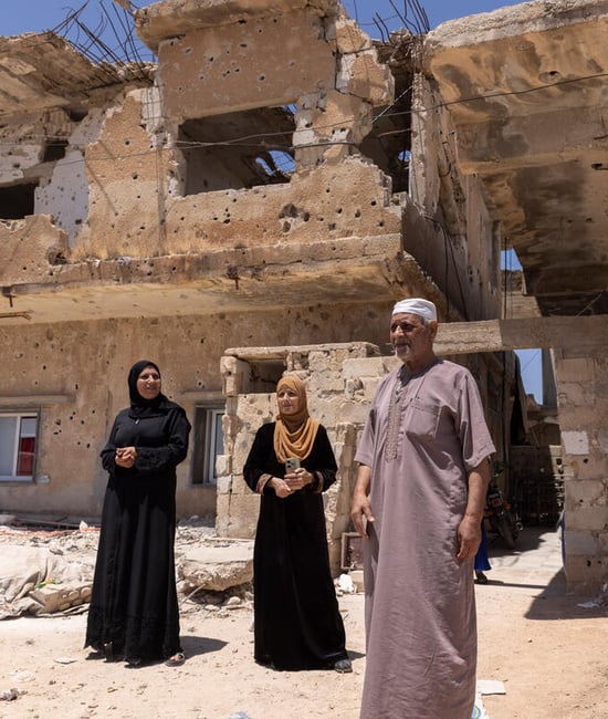 A family of four refugee returnees stand in front of a partially-collapsed building – their home in Daraa, southern Syria