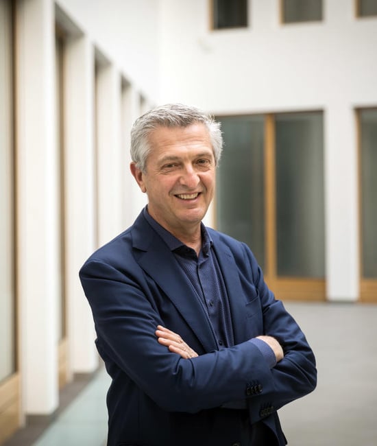 UN High Commissioner for Refugees, Filippo Grandi, stands smiling with his arms crossed.