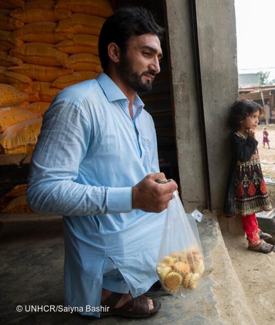 A man holding a bag full of fruits.