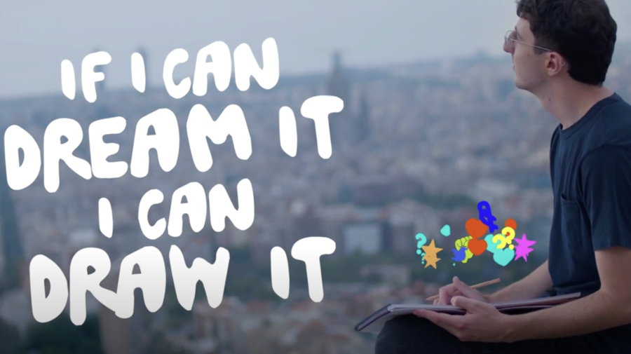 A young man sitting on the ground and holding a pen and paper in his hands. Text reads "If you can dream it you can draw it".