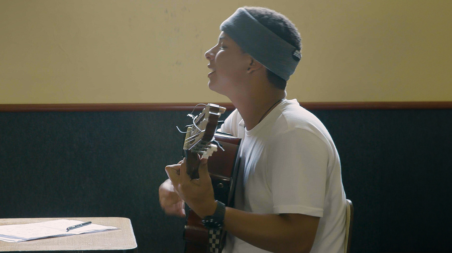 A young man playing the guitar while singing